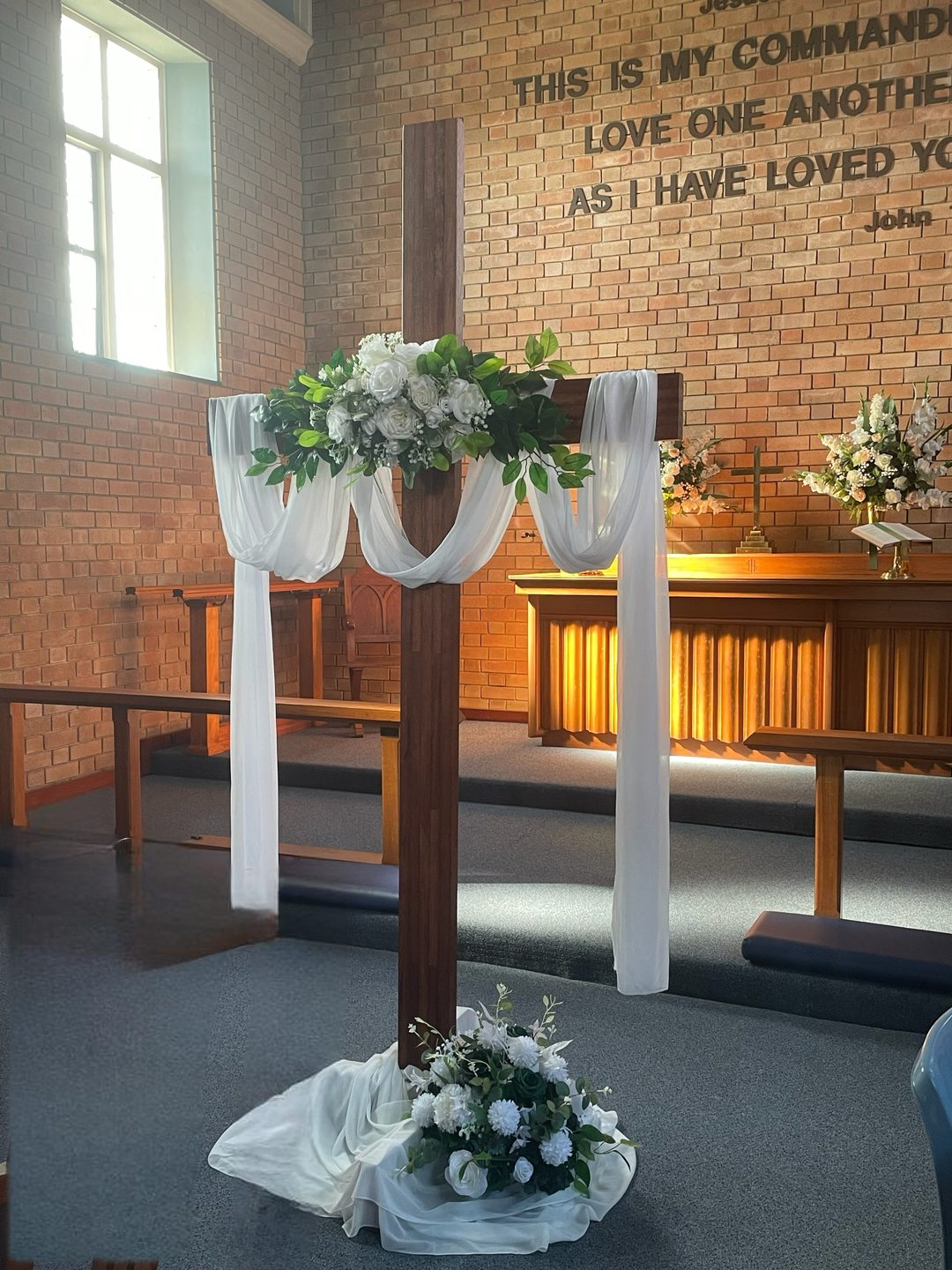 Cross arbour with white florals and draping in a church